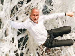 Prof. Dr. Roberst Schleip mit weißem Hemd und Jeans hängt in einem Faszienmodell